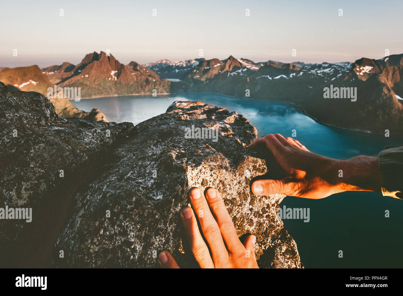 Manos del hombre subiendo hasta la cumbre de montaña aventura extrema en el estilo de vida activo vacaciones en Noruega Foto de stock