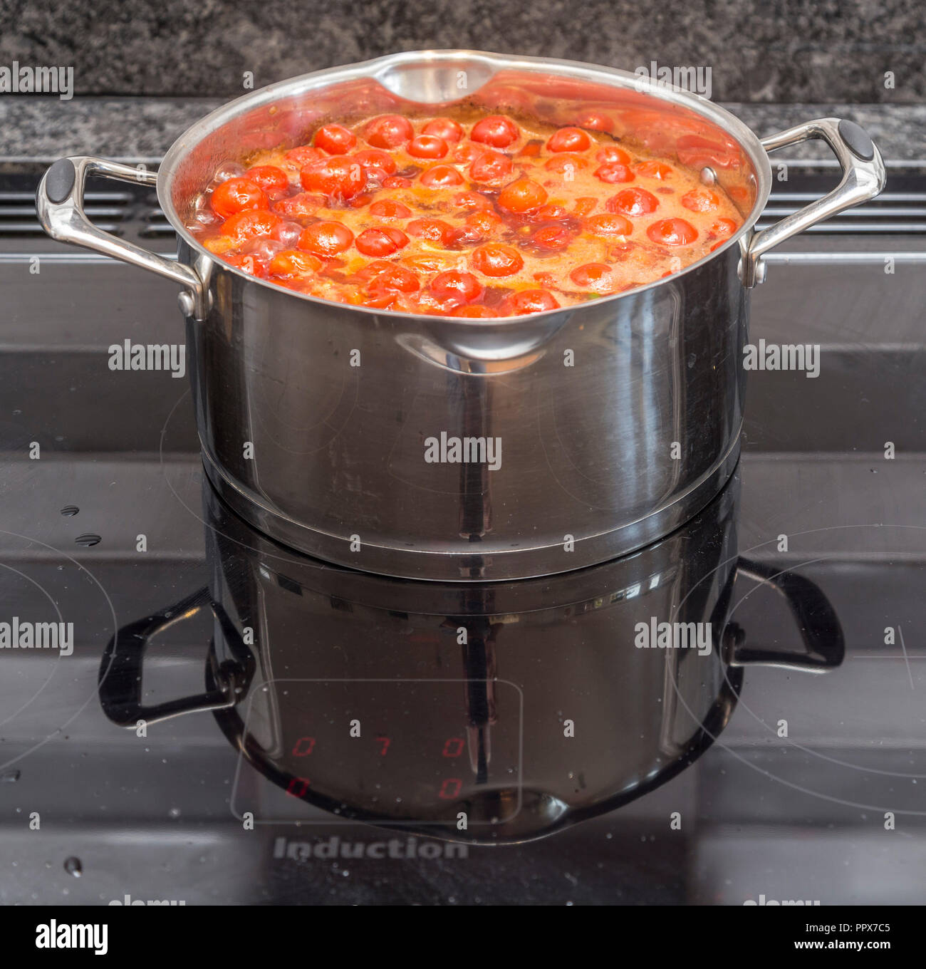 Hervir una olla grande llena de tomates en una placa de inducción hacer  sopa de tomate Fotografía de stock - Alamy