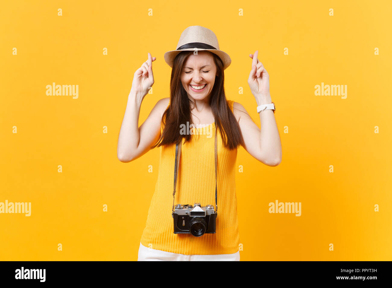 Mujer turístico en verano ropa casual hat mantener los dedos cruzados, los  ojos cerrados aislado sobre fondo amarillo. Pasajera que viajan al  extranjero a trave Fotografía de stock - Alamy