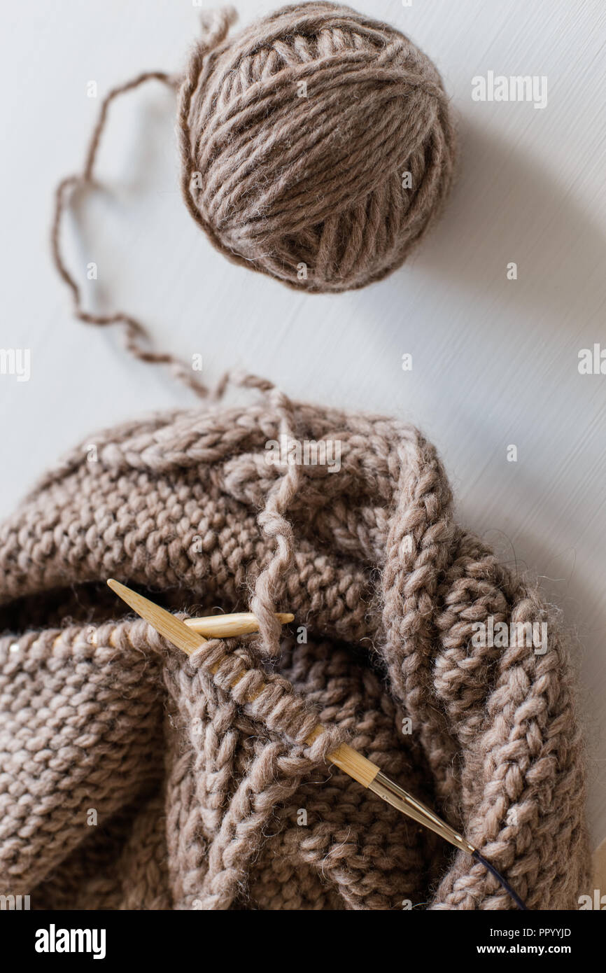 Beige tejer lana y agujas de tejer sobre fondo de madera blanca. Tejiendo  como un hobby. Accesorios para tejer Fotografía de stock - Alamy