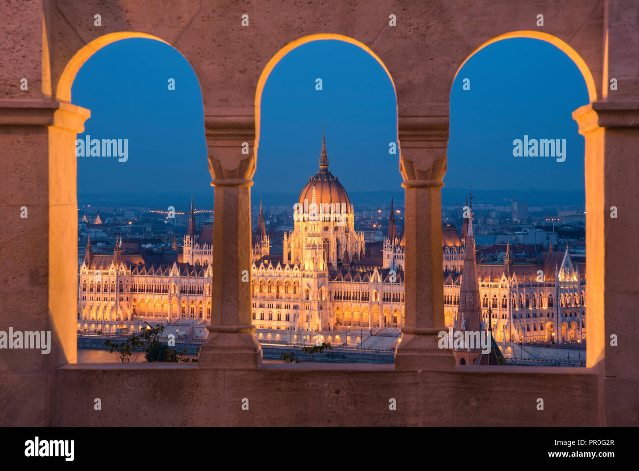 El Parlamento húngaro en la noche, visto desde las columnas y las ventanas del Bastión de los pescadores, Sitio del Patrimonio Mundial de la UNESCO, Budapest, Hungría, Europa Foto de stock