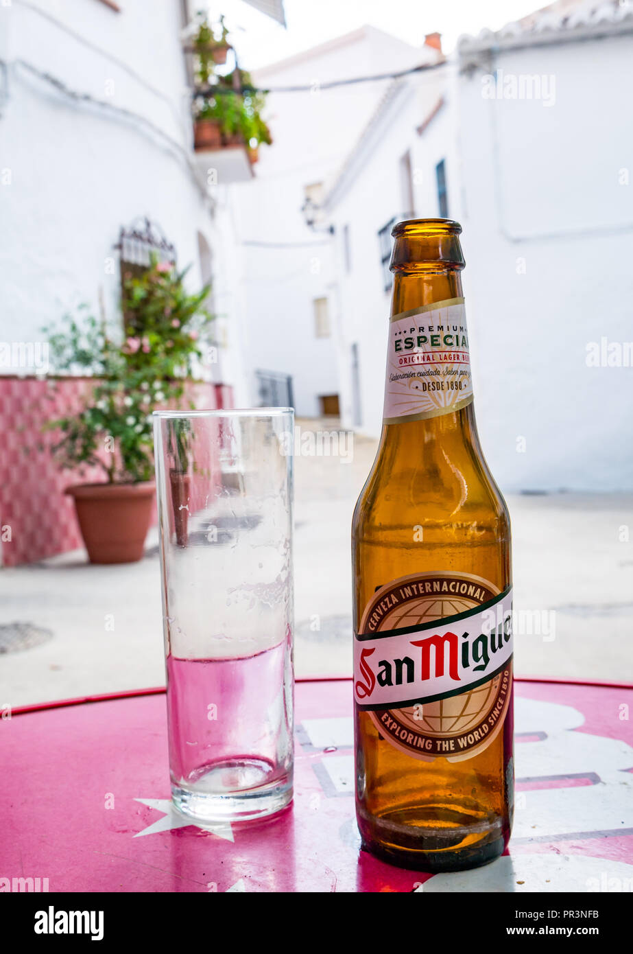 Primer plano de un vaso vacío y una botella de cerveza San Miguel en la barra tabla, Salares, Axarquía, Andalucía, España. Foto de stock
