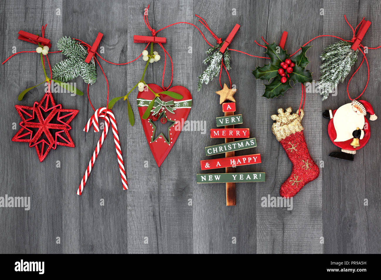 Árbol de Navidad Adornos colgantes de adorno en una línea de cadena con  flora invierno cubierto de nieve sobre fondo de madera rústica. Fiestas  Fotografía de stock - Alamy