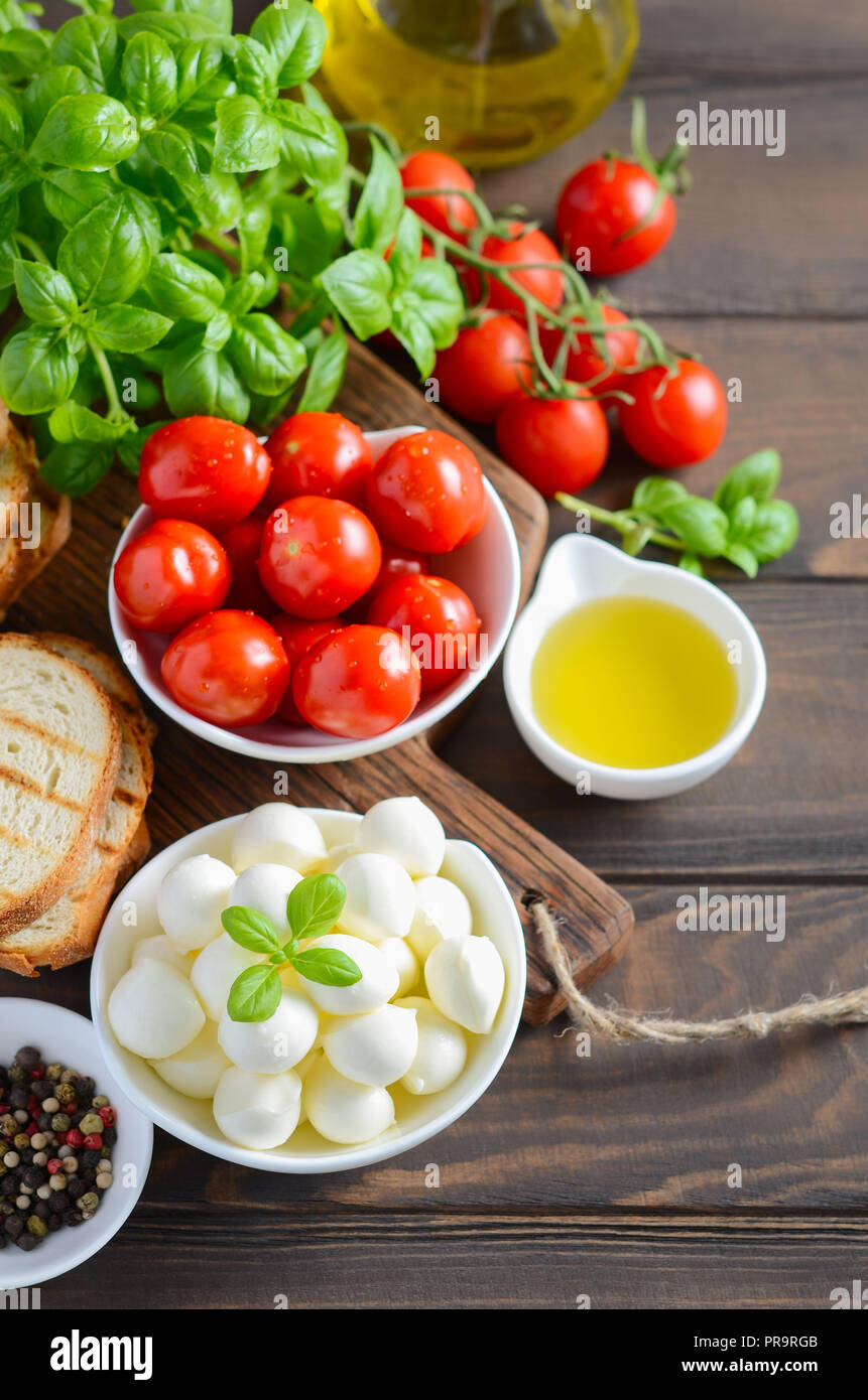 Ingredientes de comida italiana - mozzarella, tomate, albahaca y aceite de oliva sobre la mesa de madera rústica. Foto de stock