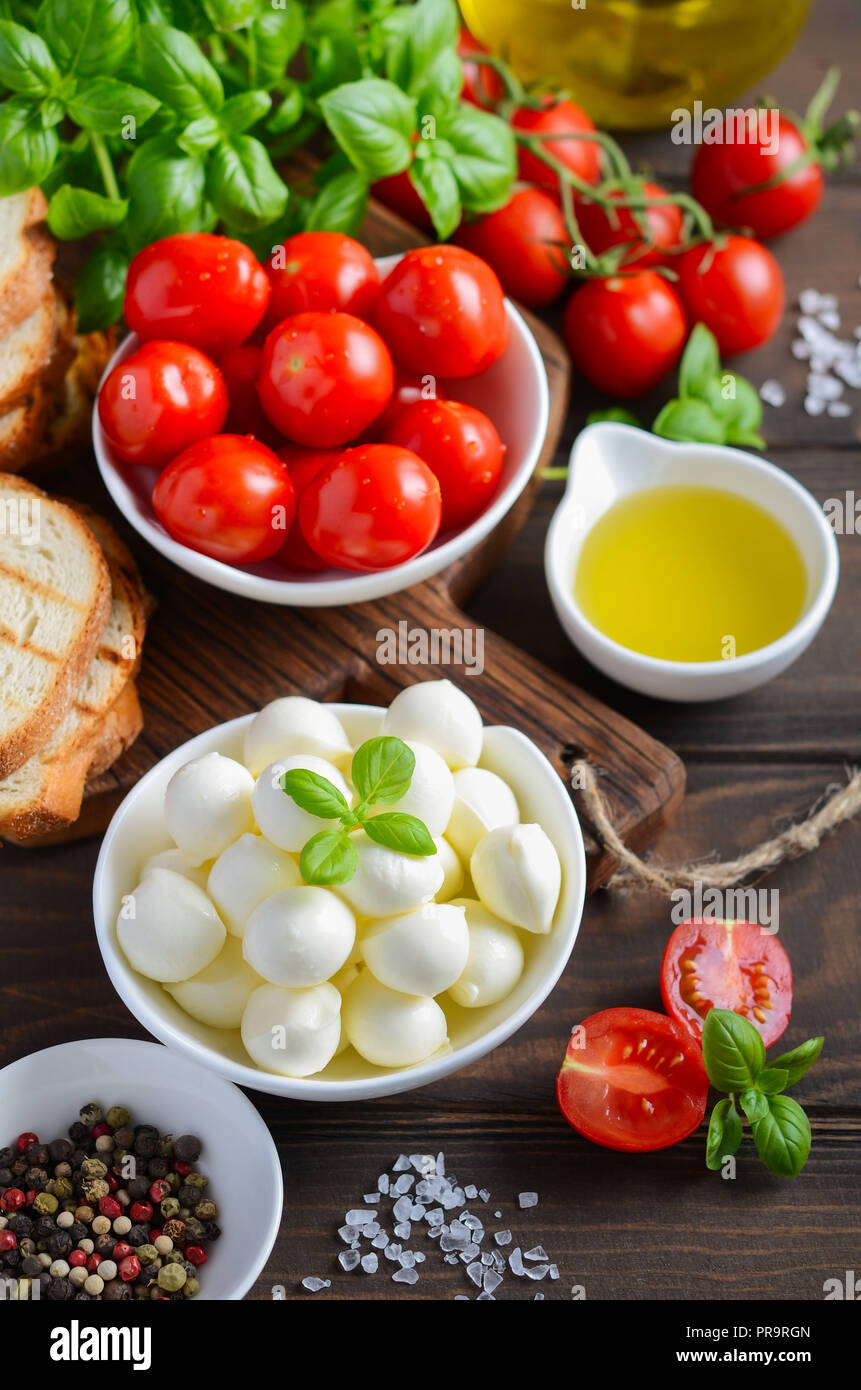 Ingredientes de comida italiana - mozzarella, tomate, albahaca y aceite de oliva sobre la mesa de madera rústica. Foto de stock