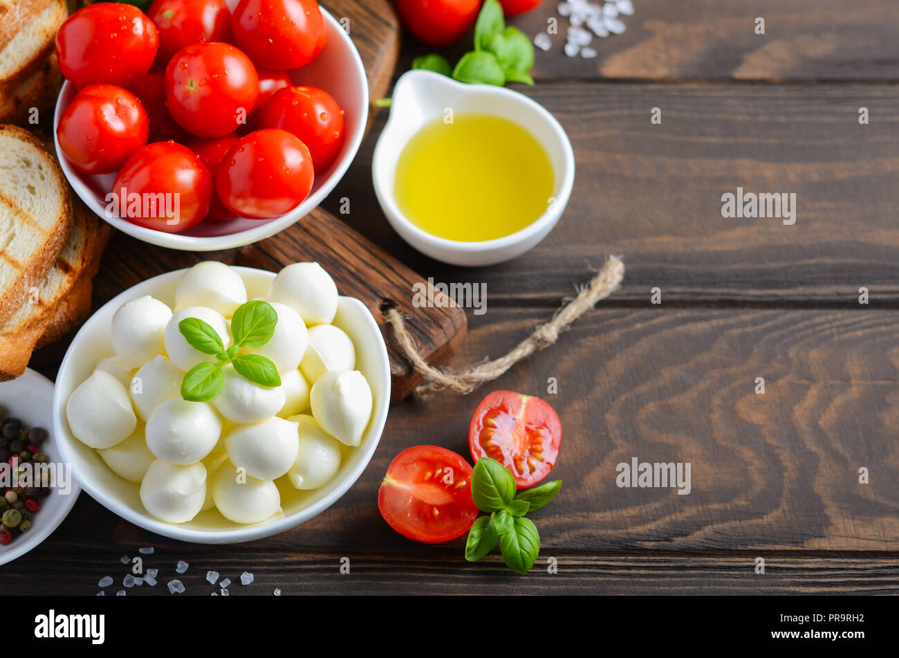 Ingredientes de comida italiana - mozzarella, tomate, albahaca y aceite de oliva sobre la mesa de madera rústica. Foto de stock