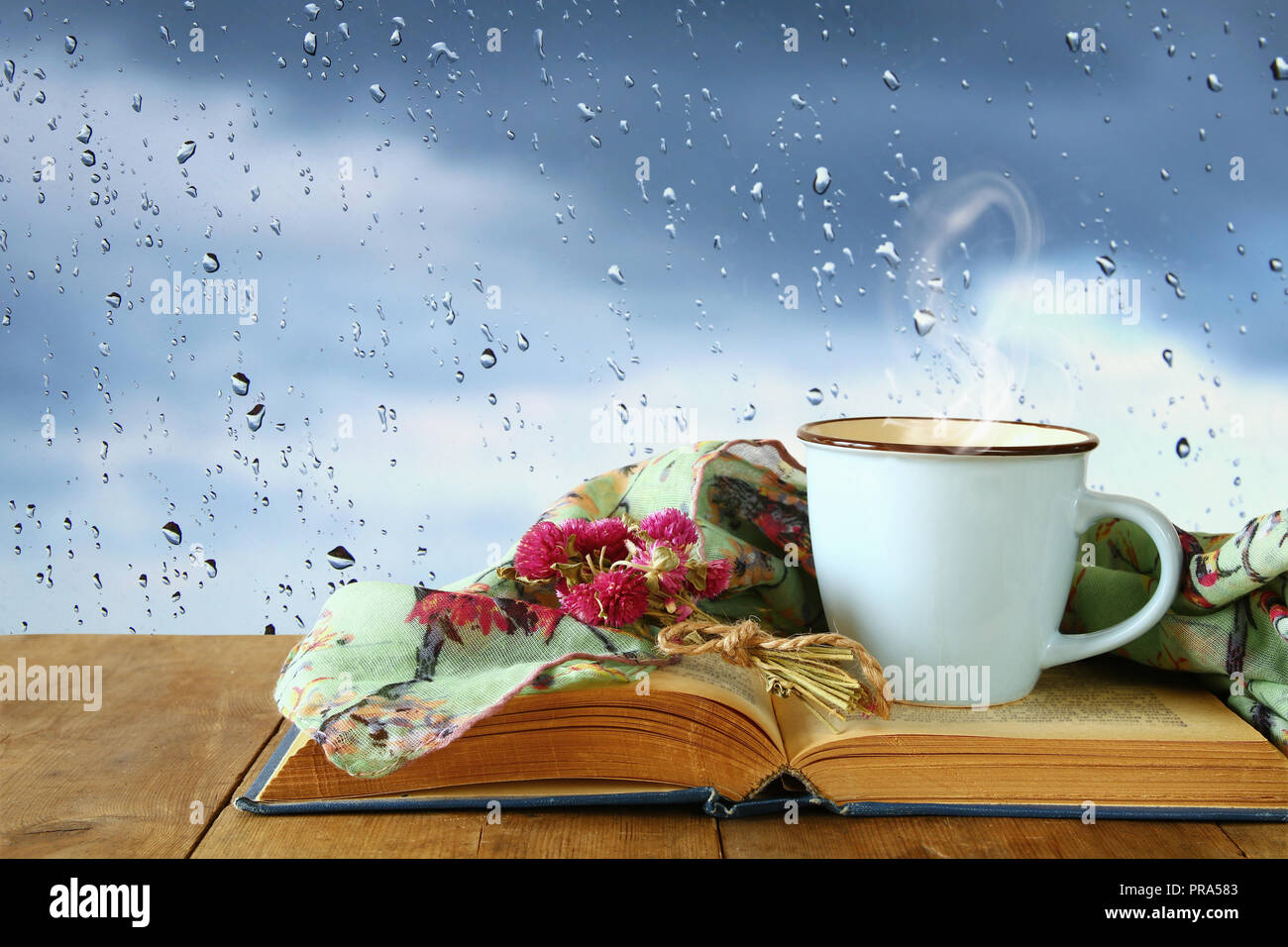 La taza de café en un día lluvioso en mesa de madera y cristal con gotas de  lluvia antecedentes Fotografía de stock - Alamy