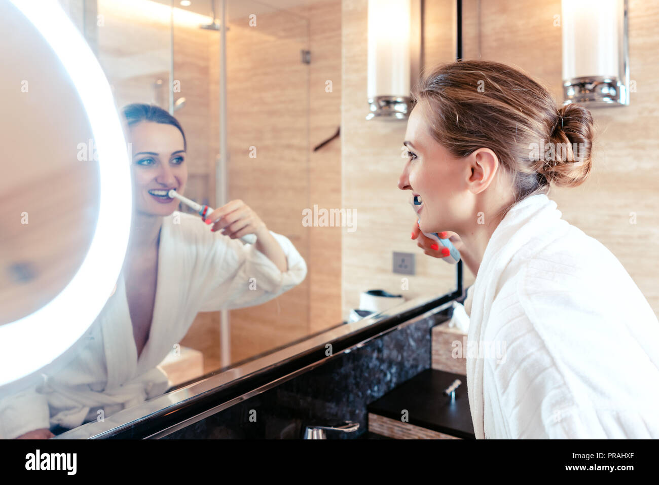 Mujer cepillando sus dientes en un lujoso hotel mirando a sí misma Foto de stock
