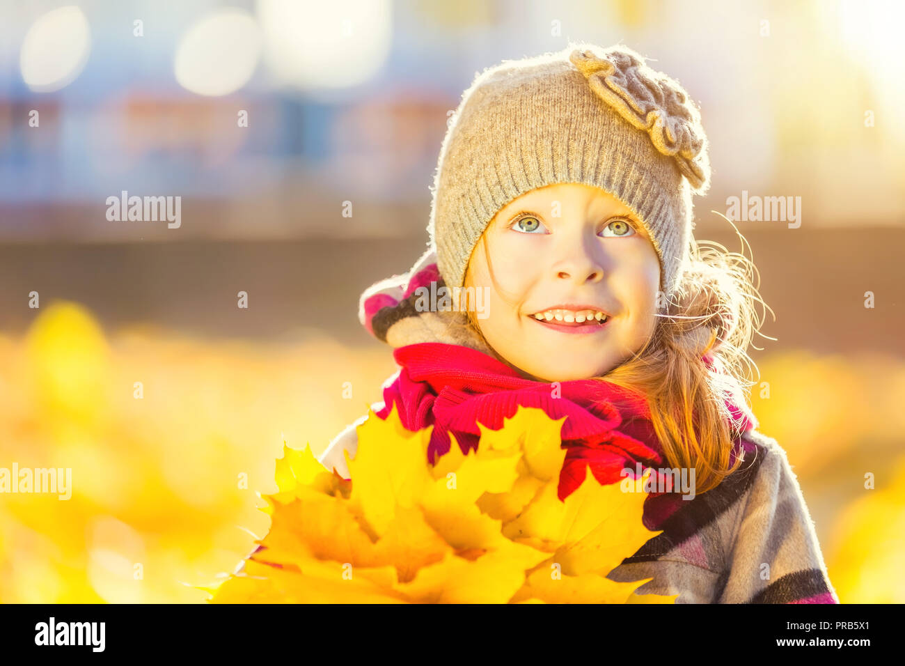 Feliz niña en orejeras con hojas de otoño Fotografía de stock - Alamy