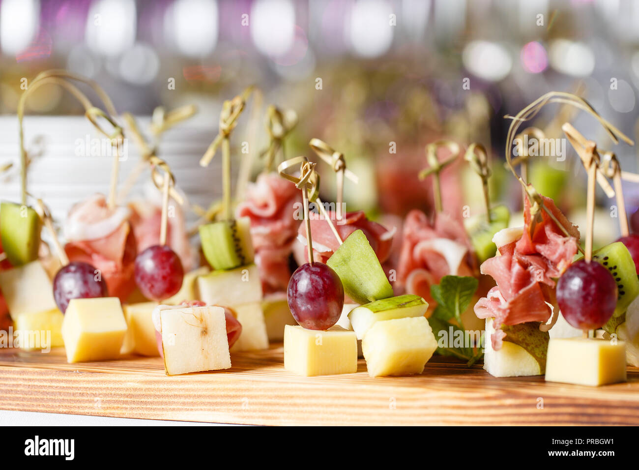 El buffet en la recepción. Surtido de canapés sobre la plancha de madera. Servicio de banquetes catering comida, aperitivos con queso, jamón, jamón y fruta Foto de stock