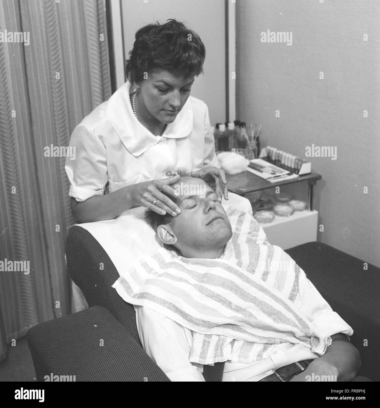Cuidados de belleza en la década de 1950. Una joven mujer es masajear la cabeza de un hombre. Suecia, junio de 1959 Foto de stock