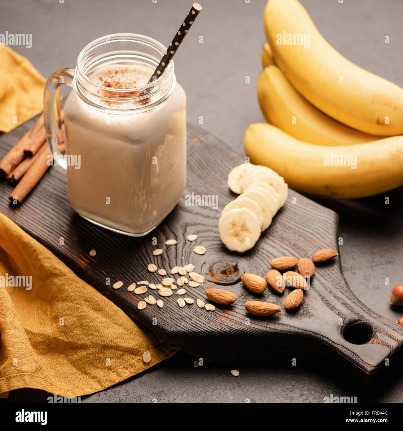Banana smoothie o batido de proteínas con avena, leche de almendras en  madera sirviendo a bordo. Recortar cuadrados, el enfoque selectivo  Fotografía de stock - Alamy