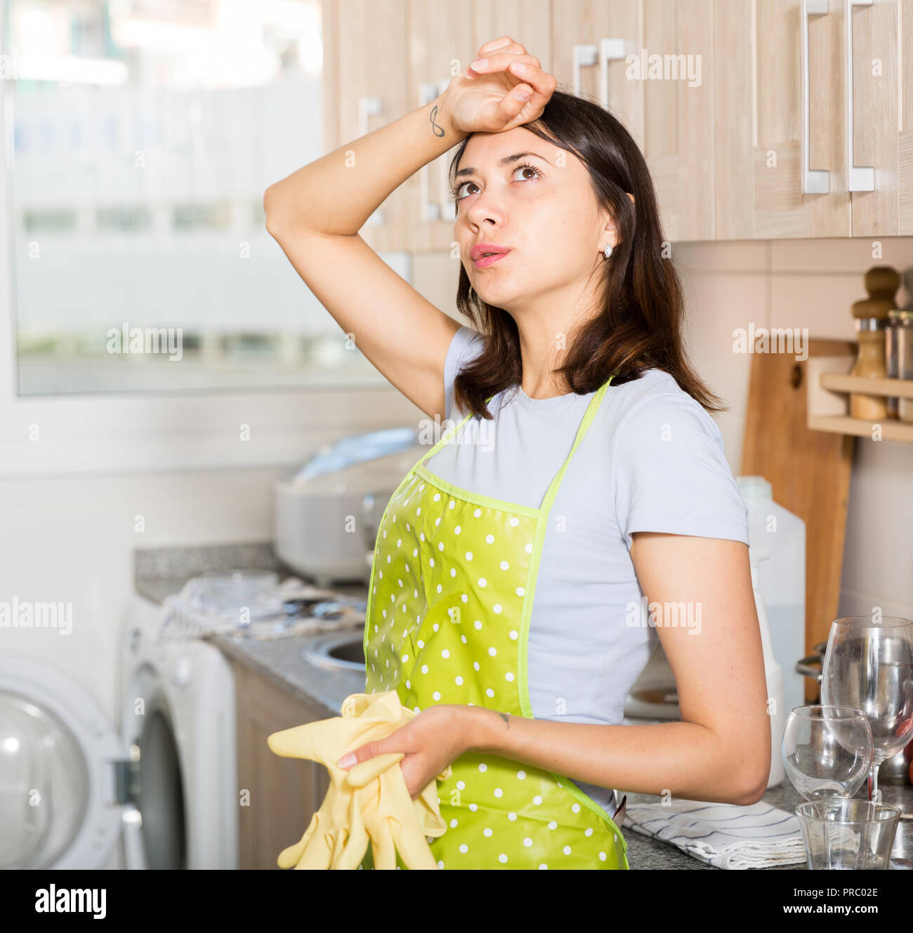Chica cansada delantal de ama de casa en la celebración de los guantes de  cocina en casa Fotografía de stock - Alamy