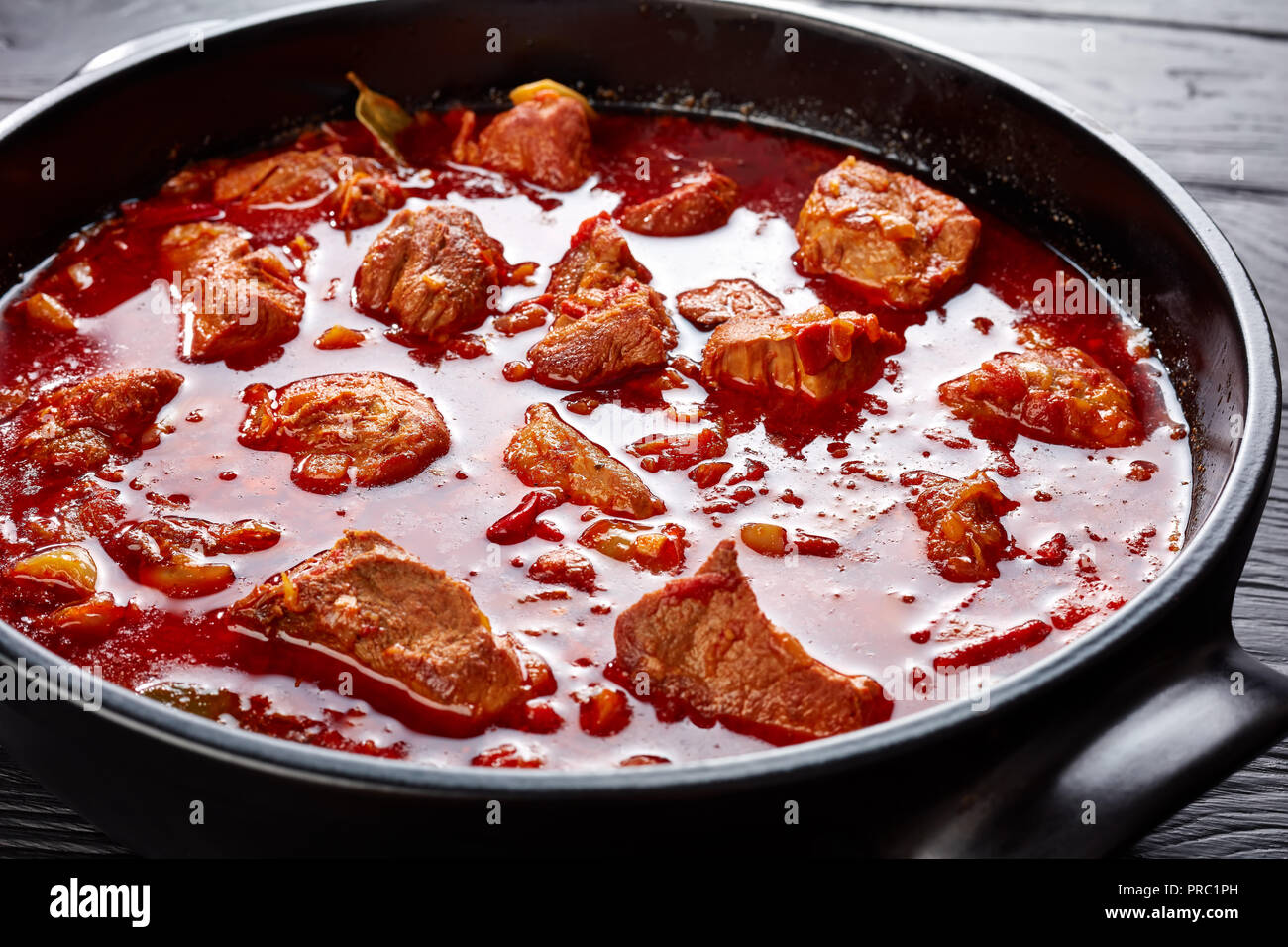 Abundante de chile rojo y carne de cerdo estofado o carne adobada en un  horno holandés, sobre una tabla de madera negra, cocina mexicana, vista  horizontal desde arriba, close-up Fotografía de stock -