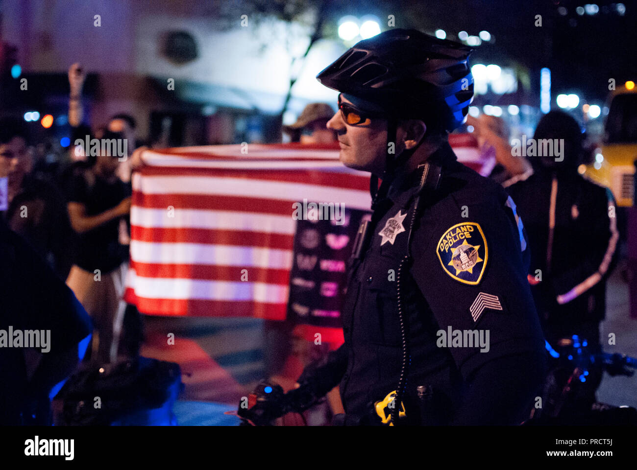 Un oficial de la policía de Oakland bicicleta relojes de los manifestantes contra la elección del presidente Donald Trump en el centro de las protestas del 9 de noviembre de 2016. Foto de stock