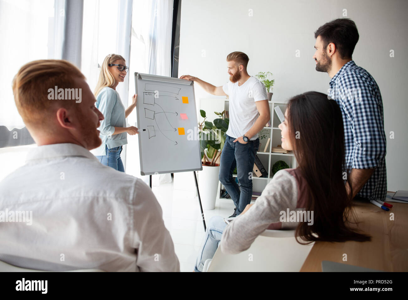 El desarrollo de la nueva estrategia. Dos jóvenes colegas realizando presentación mientras trabaja con su equipo comercial en la oficina. Foto de stock