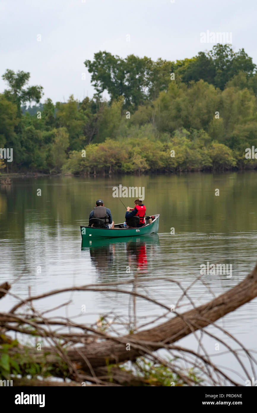 BOSSIER CITY, LA., EE.UU. - 29 de septiembre, 2018: un hombre y el muchacho se ven desde la parte trasera en una canoa en un hermoso y tranquilo lago durante un viaje de pesca. Foto de stock