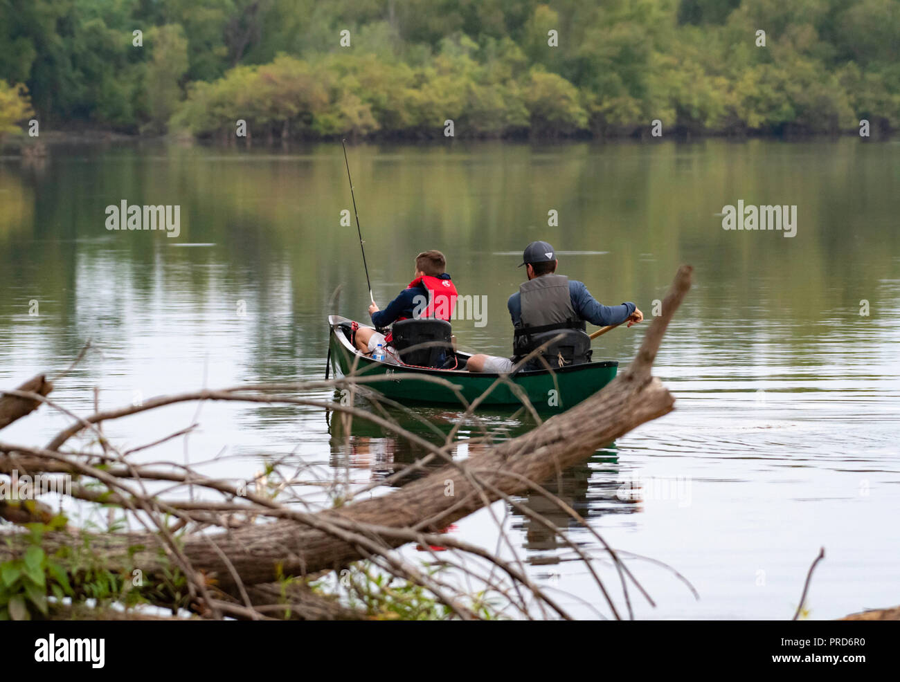 BOSSIER CITY, LA., EE.UU. - 29 de septiembre, 2018: un hombre y el muchacho se ven desde la parte trasera en una canoa en un hermoso y tranquilo lago durante un viaje de pesca. Foto de stock