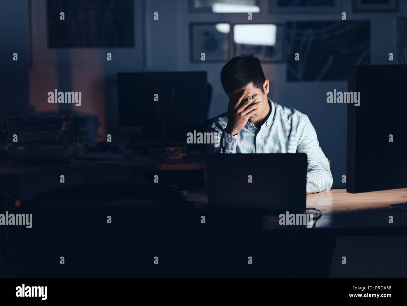 Agotado empresario asiático trabajar hasta tarde en la noche en una oficina. Foto de stock