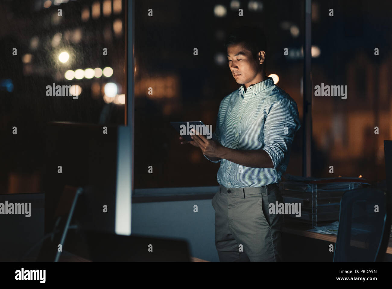Empresario asiático utilizando una tableta digital a altas horas de la noche Foto de stock