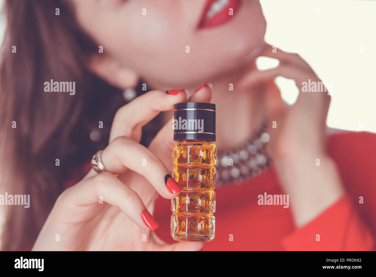 Mujer de vestido rojo sostiene una botella de perfume Fotografía de stock -  Alamy