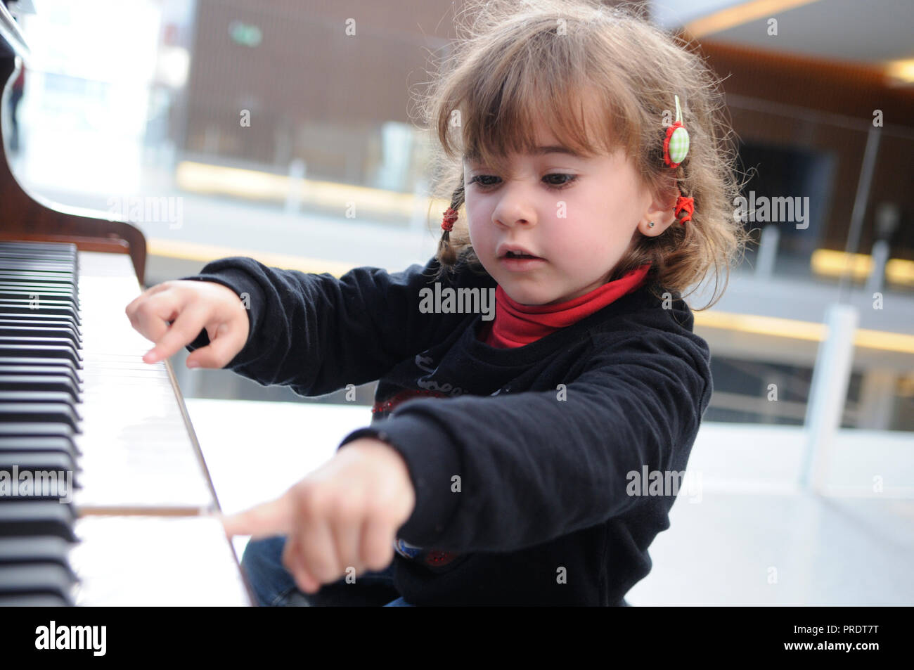 Adorable niña divertirse tocando el piano Foto de stock