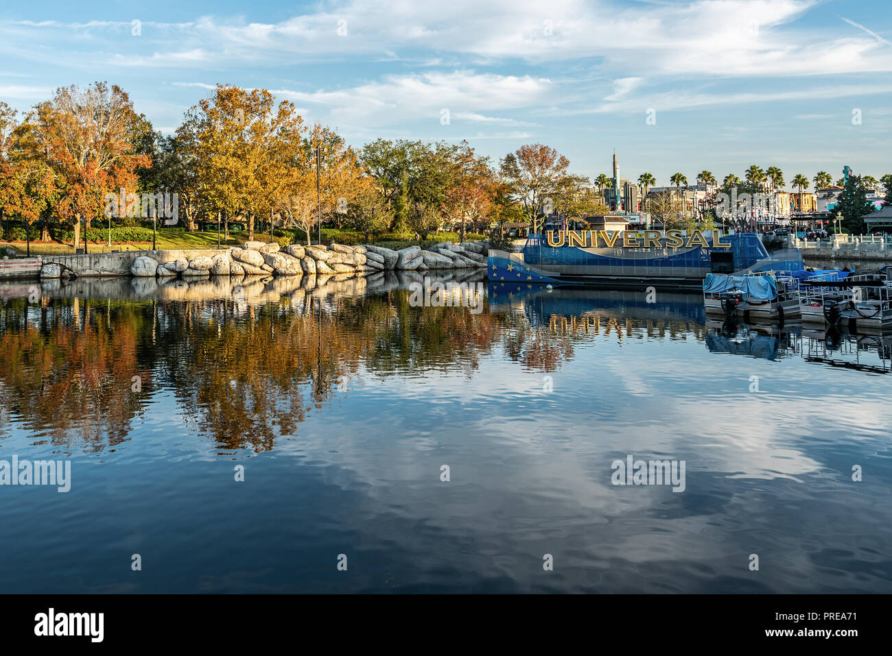 ORLANDO, Florida, EE.UU. - Diciembre, 2017: Amarillo árboles en un cielo azul del reflejo en el agua en Universal Studios Florida Foto de stock