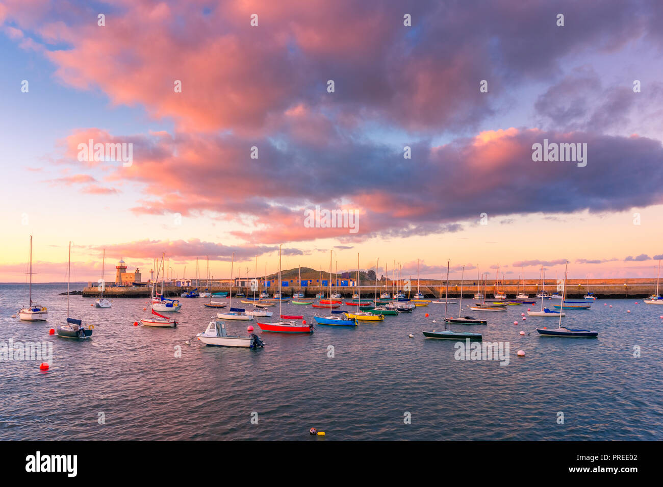 Increíble atardecer en Howth, Dublín, Irlanda. Las vistas de Howth Faro y coloridas embarcaciones en primer plano. Foto de stock