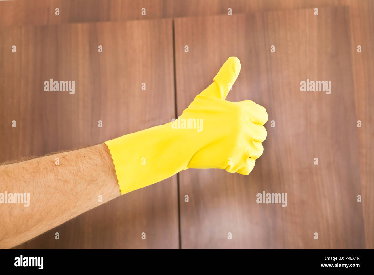 Limpieza de éxito. Thumbs up de mano en guante de protección amarilla Foto de stock