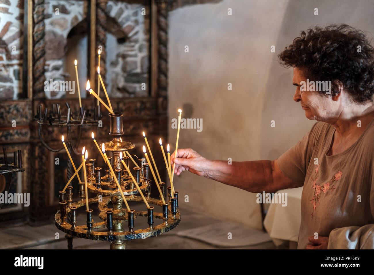 Senior Mujer encendiendo una vela en la iglesia ortodoxa. Foto de stock
