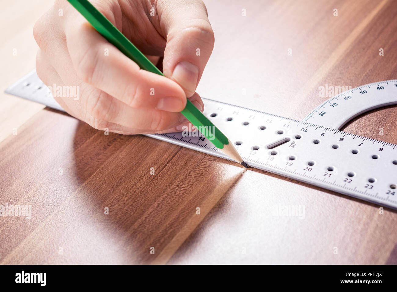 Carpintero utilizando un transportador y hacer una marca en el punto de  medición con un lápiz sobre una tabla de madera Fotografía de stock - Alamy