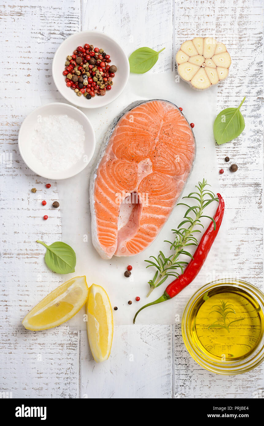 Filete de salmón fresca cruda con limón, aceite de oliva y especias sobre fondo de madera de estilo rústico. Ingredientes para hacer la cena saludable. Concepto de dieta saludable. Foto de stock