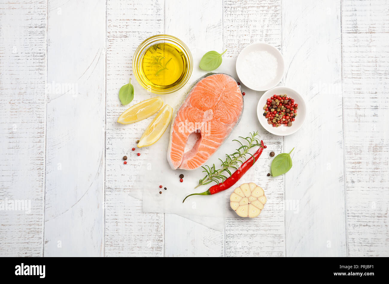 Filete de salmón fresca cruda con limón, aceite de oliva y especias sobre fondo de madera de estilo rústico. Ingredientes para hacer la cena saludable. Concepto de dieta saludable. Foto de stock