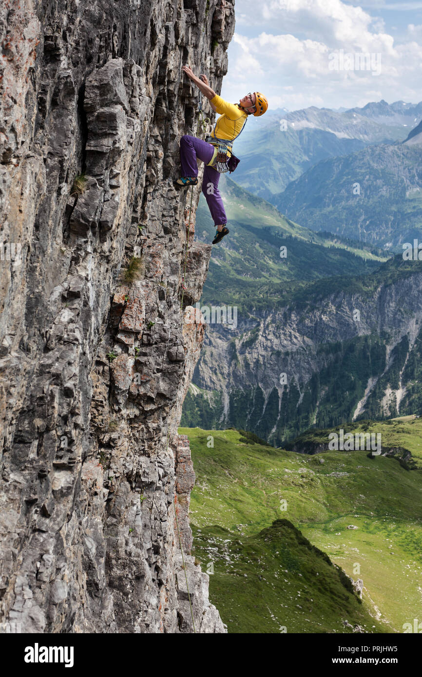Una mujer sube una roca vertical, nivel de dificultad 6, Angererkopf, cabaña alpina Mindelheim, Alpes Allgäu, Baviera, Alemania Foto de stock