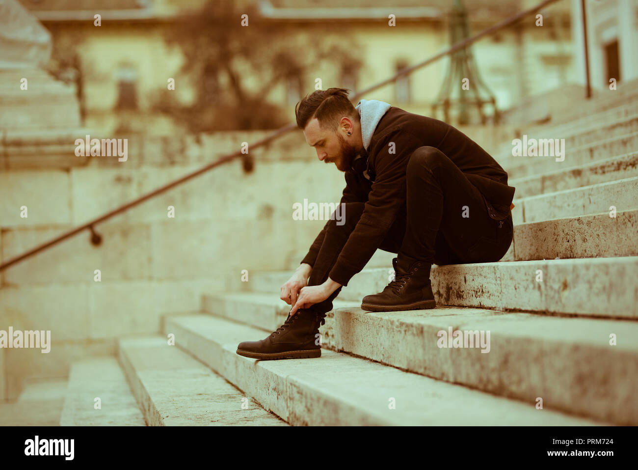 Estilo retro foto de un joven hipster hombre sentado en las escaleras y  atar sus zapatos Fotografía de stock - Alamy