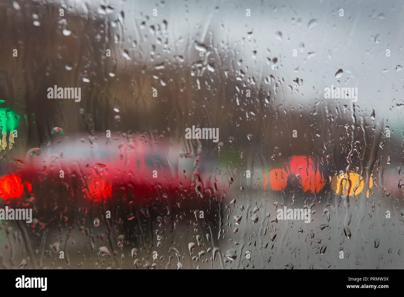 Vista de la calle a través de las gotas de lluvia en el cristal de coche Foto de stock