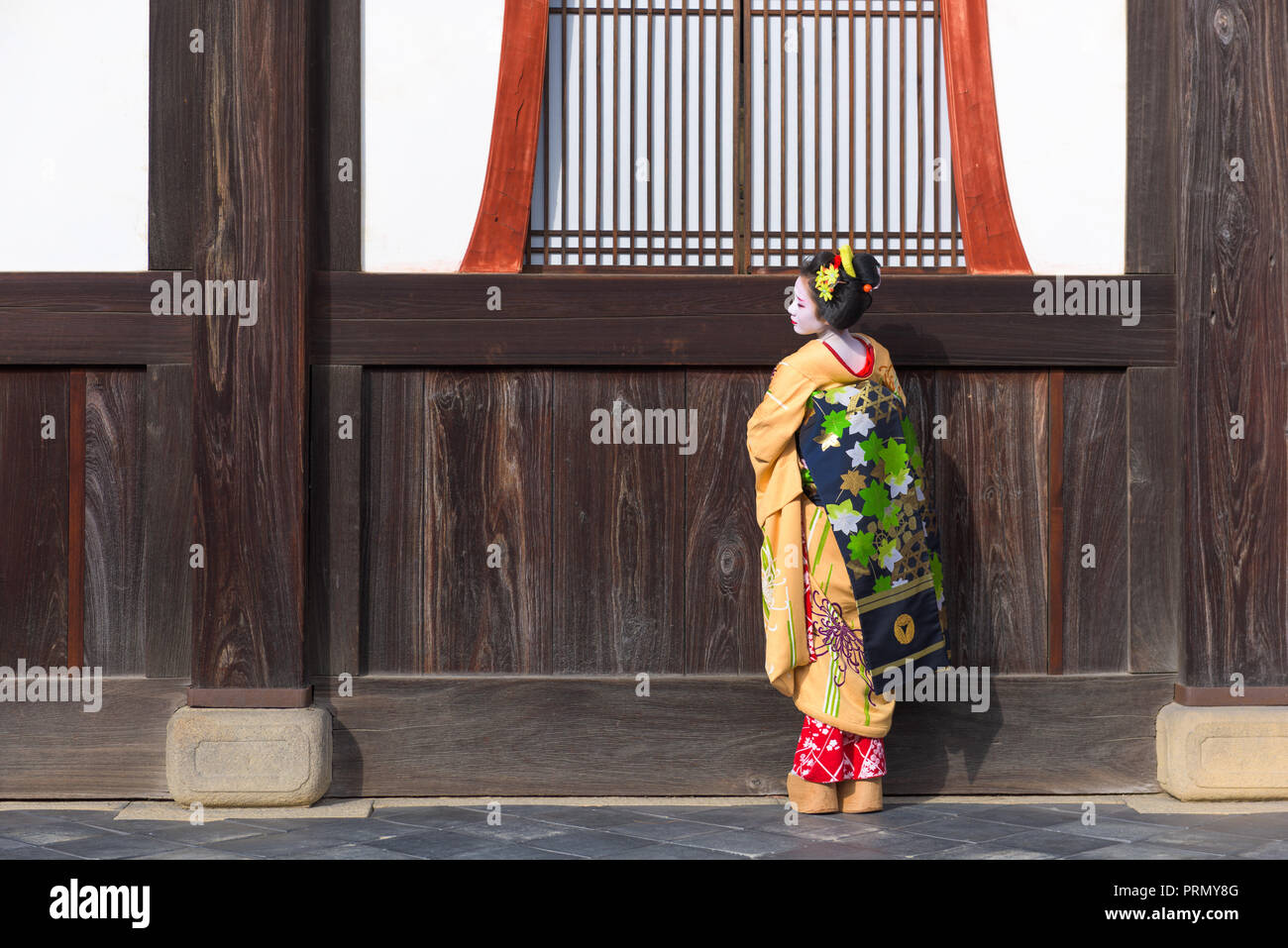 KYOTO, Japón - Noviembre 28, 2015: Una mujer en el tradicional vestido de Maiko parece fuera de un templo umbral. Foto de stock