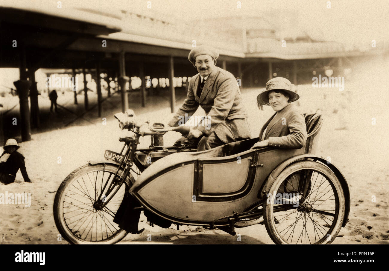 Lady & Gentleman en 1910 Triumph & sidecar combinación en la playa al lado de un muelle en la Costa circa 1910 Foto de stock