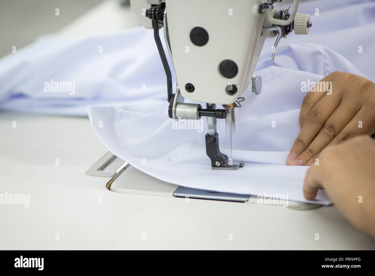 Costurera de una máquina de coser hace una camisa en el taller de costura.  La mujer en la máquina cose el cuello y puños Fotografía de stock - Alamy