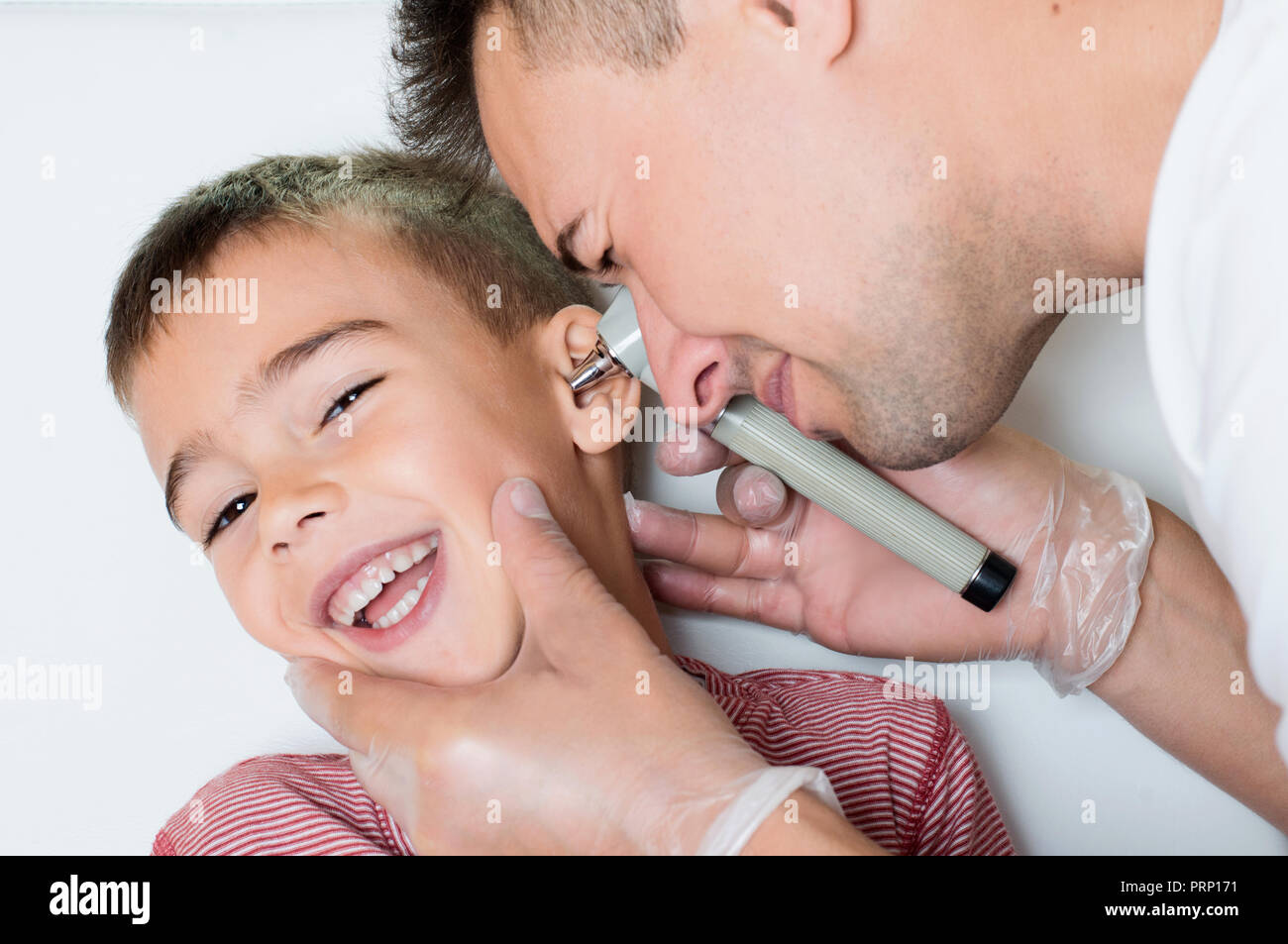 Doctor explora el oído al niño sonriente Foto de stock