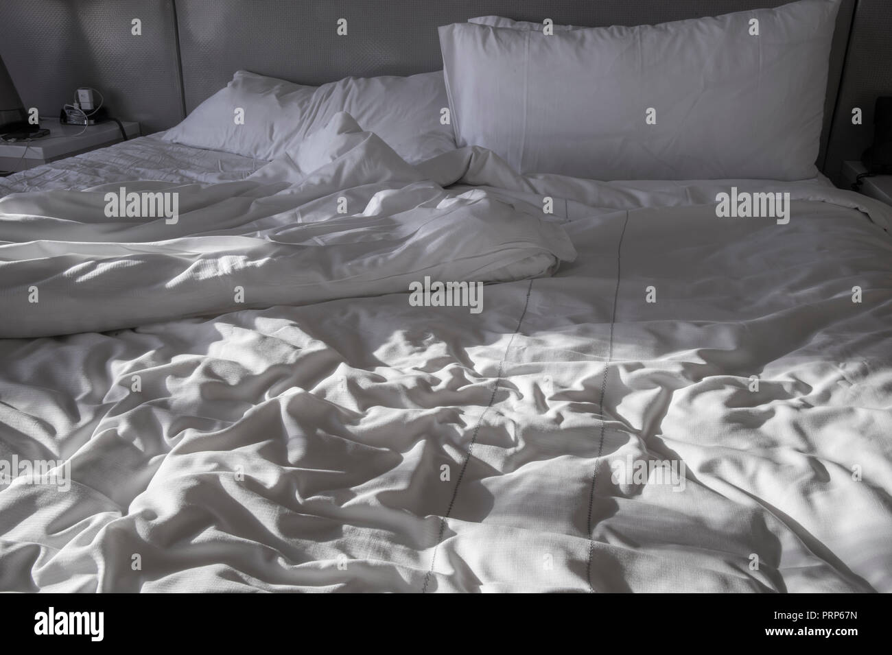 Cama con sábanas dormido en la luz del sol de la mañana Foto de stock