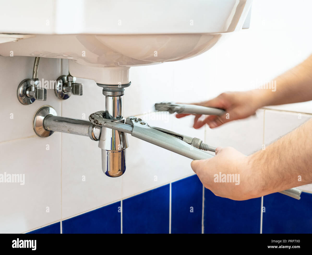 Fontanero ajusta dos llaves de tubo para instalar un sifón de lavabo en el  baño Fotografía de stock - Alamy