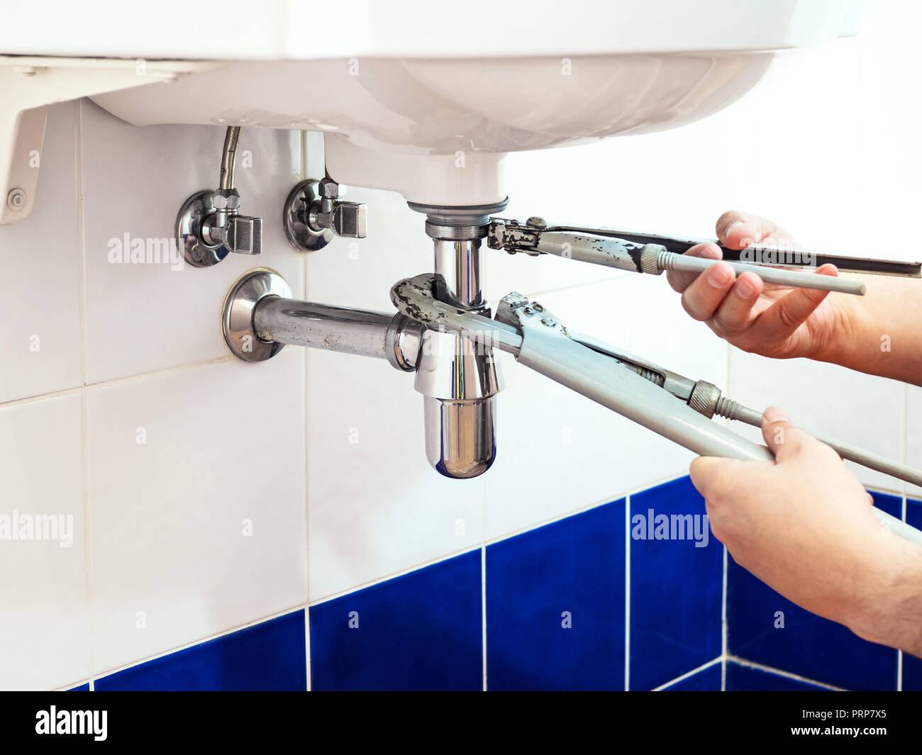 Fontanero fija dos llaves de tubo para instalar un sifón de lavabo en el  baño Fotografía de stock - Alamy