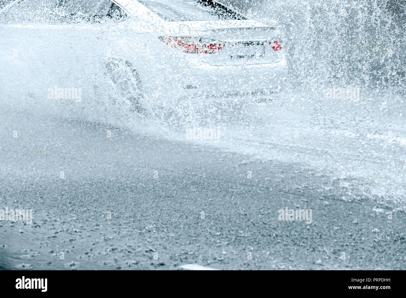 Las salpicaduras de agua de lluvia desde el coche las ruedas mientras se mueve por la City Road durante la lluvia pesada Foto de stock