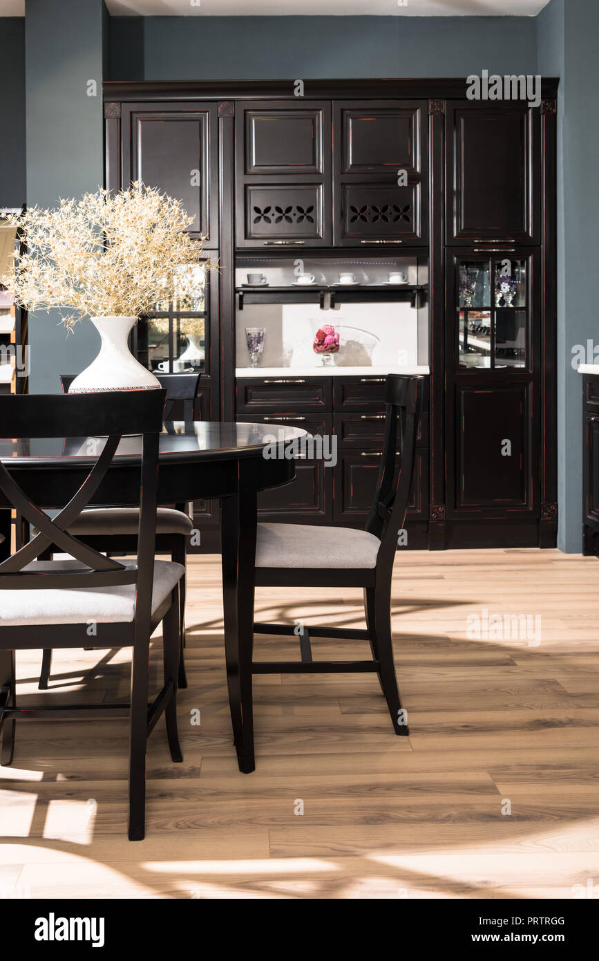 Interior del comedor moderno con muebles negros, Jarrón de flores secas  sobre la mesa y piso de madera Fotografía de stock - Alamy