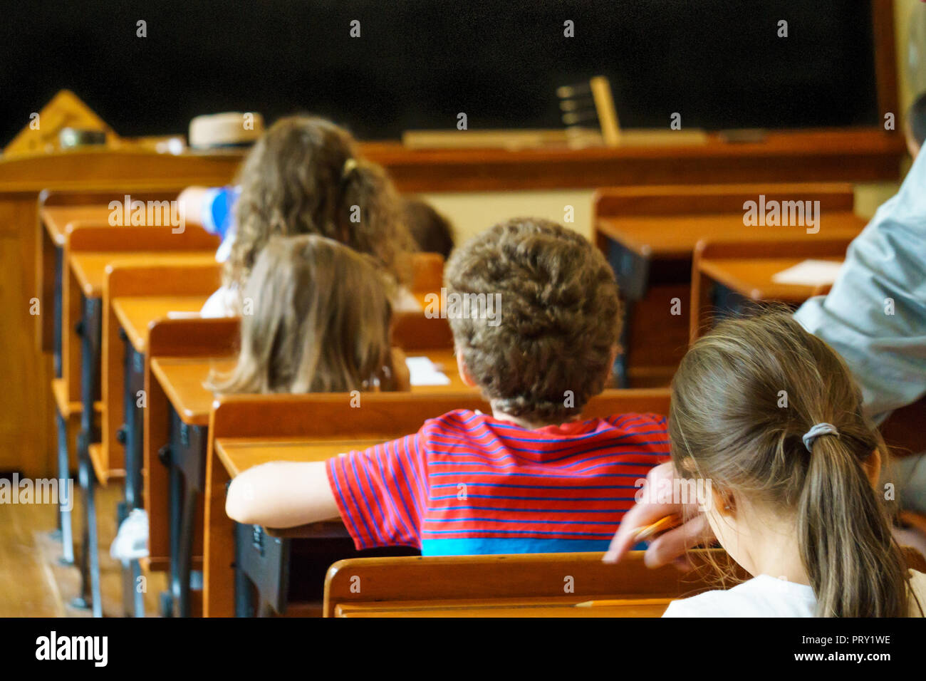 Grupo de escolares sentados en escritorios y escuchando al profesor durante la lección en el aula. Maestro indica un error. Foto de stock