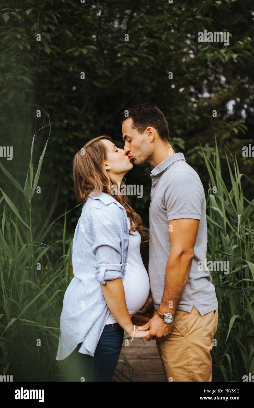 Pareja embarazada tomarse de las manos y besarse mutuamente Fotografía de  stock - Alamy
