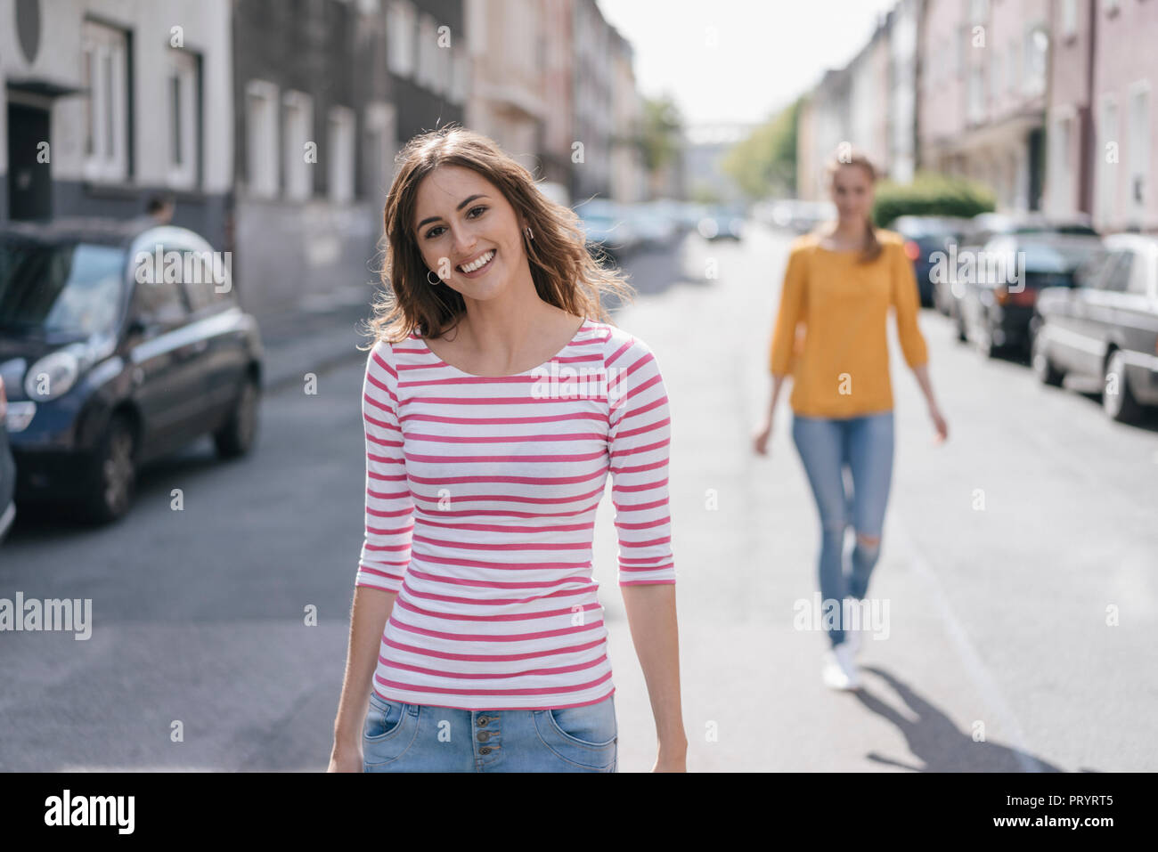 Mujer caminando por la calle, seguido por el amigo Foto de stock