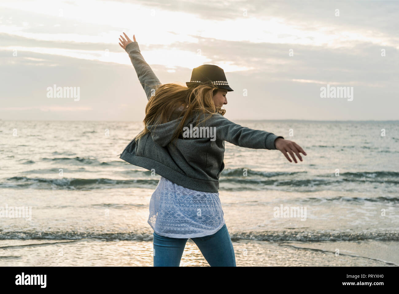 Feliz mujer joven en la playa en el atardecer. Foto de stock