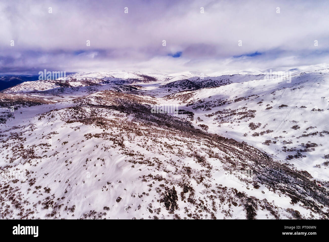Blancos como la nieve, las laderas de las montañas más altas en Australia bajo las nubes blancas a lo largo de Perisher Valley con una gruesa capa de nieve y esquí pistas deportivas. Foto de stock